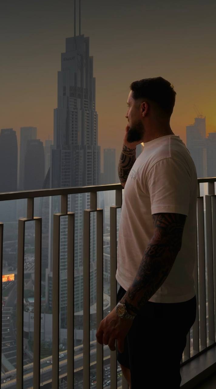 Ionut on a high-rise balcony at sunset, looking out over the Dubai skyline